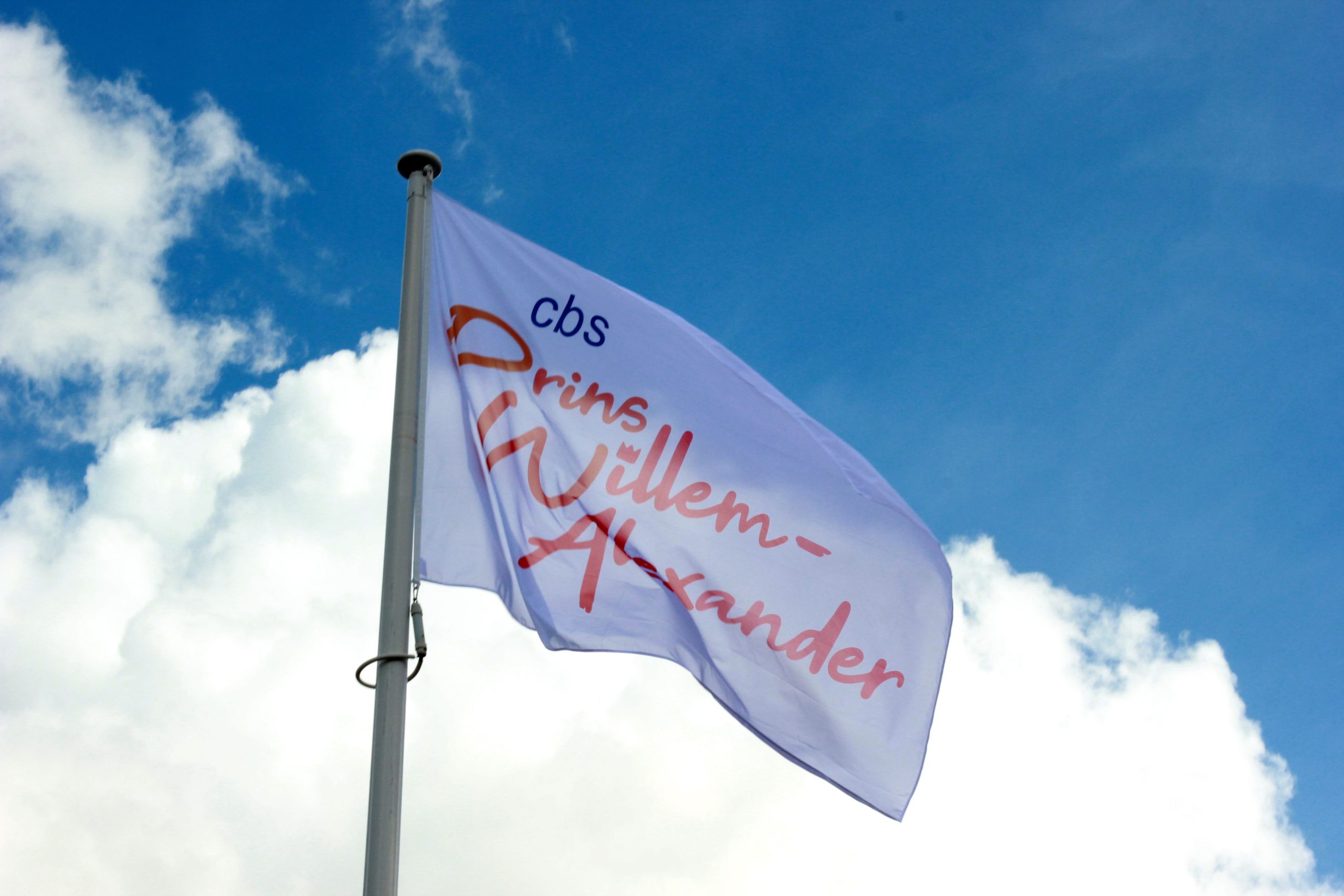 vlag met logo van de PWA , tegen een blauwe lucht met witte wolken als achtergrond